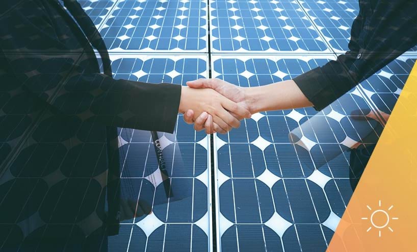 People shaking hands with solar panels in the background