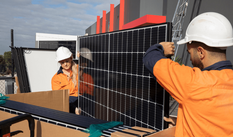 Two workers holding a solar panel. 