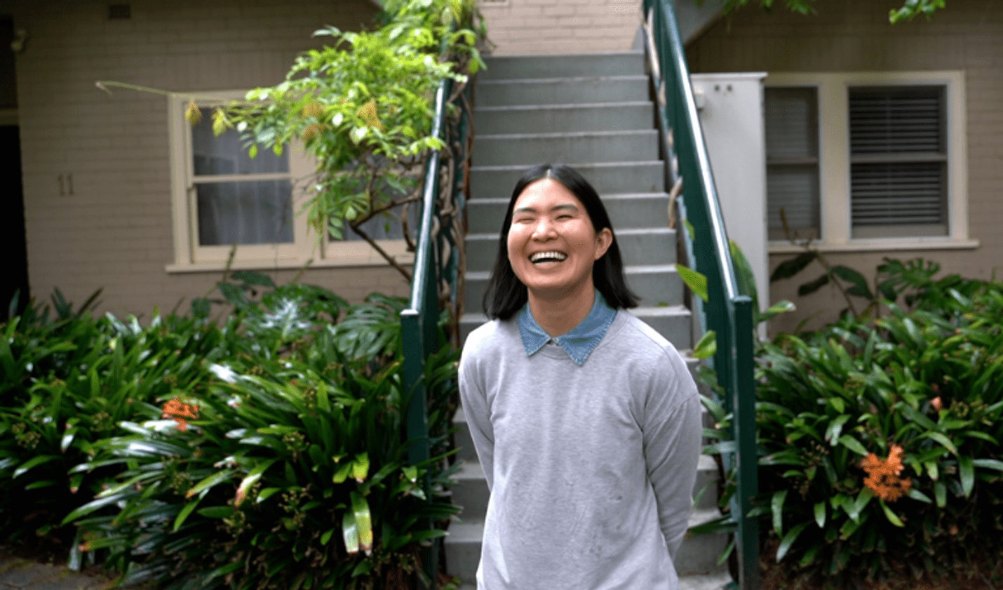 Triangle-Neighbours-Community Tia smiling in front of her townhouse with a solar panel