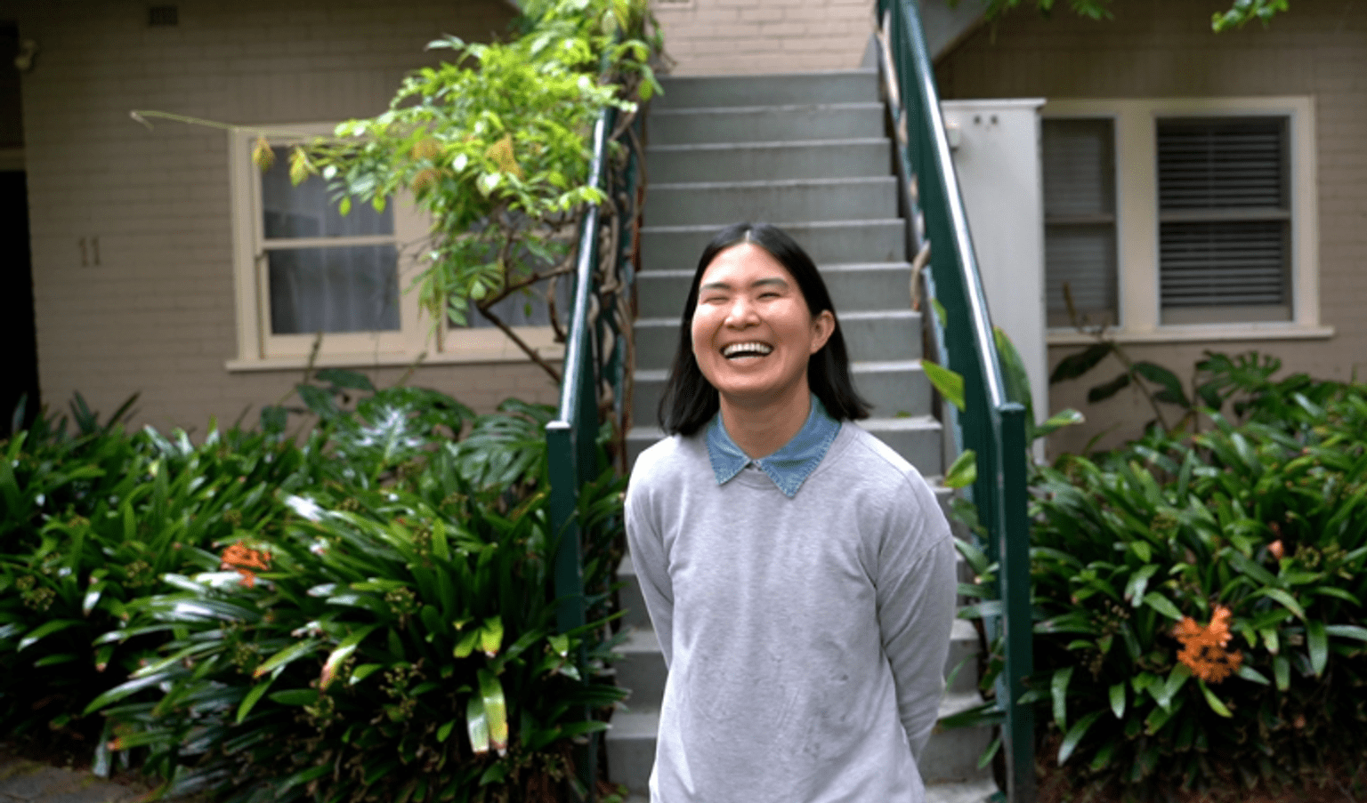 Triangle-Neighbours-Community Tia smiling in front of her townhouse with a solar panel